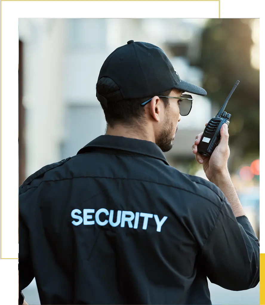 Security guard using a walkie-talkie outdoors.